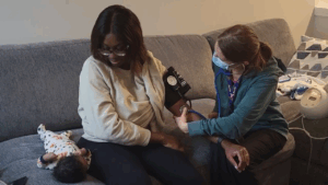 Photo of nurse performing a home visit with a mother and baby.